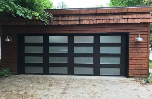 Brown building with wood siding and modern garage door with a lot of windows